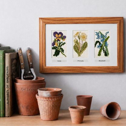Framed botanical stitched floral on a shelf with gardening tools and books